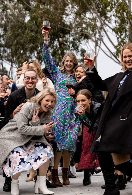 Group of people celebrating outdoors with drinks, surrounded by trees.
